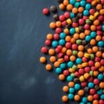 Colorful round and disc-shaped chewable supplement tablets scattered on dark background